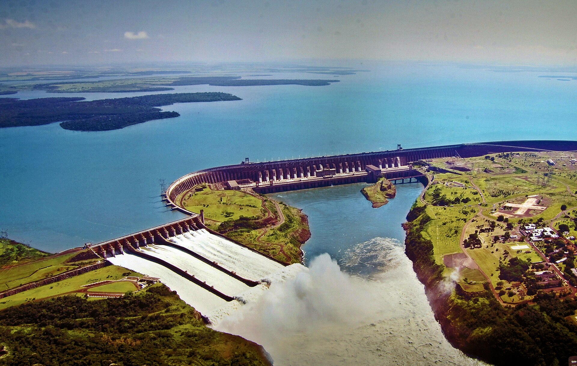 Vista aérea da barragem de Itaipu, reservatório, vertedouro aberto e a casa de força.